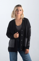 Introducing the Vital Moment Cardigan, a chic black and gray cardigan featuring unique "Dreamer" text on the sleeves. With front pockets and a button-up design, this cardigan combines comfort and style, making it a versatile addition to your wardrobe.

Fabric: 40% Acrylic, 30% Polyester, 30% PBT

Size Guide: Fits True To Size, Model is Wearing a Size S

Available at our boutiques in Chicago, Lake Geneva, and Milwaukee. (Item availability may vary by location.)