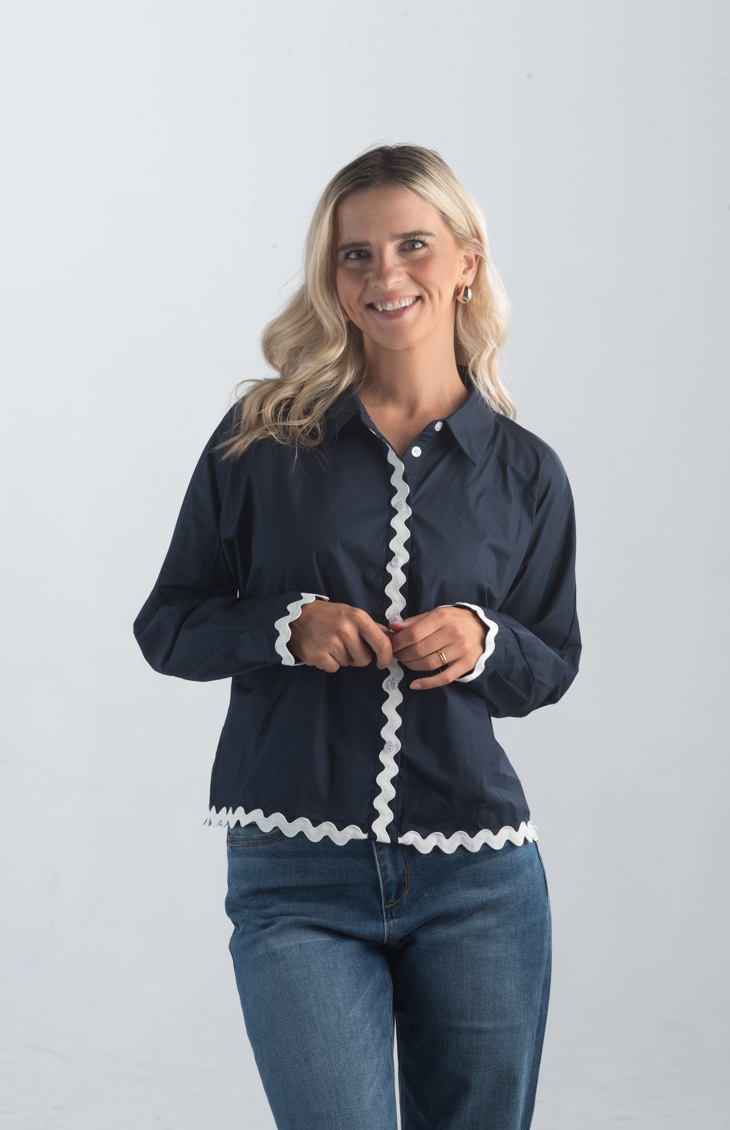 Introducing the Polly Blouse, a stylish navy blouse featuring playful white squiggly stripes. This button-down, collared blouse with long sleeves offers a timeless look, perfect for both casual and professional settings.

Fabric: 100% Cotton

Size Guide: Fits True To Size, Model is Wearing a Size S

Available at our boutiques in Chicago, Lake Geneva, and Milwaukee. (Item availability may vary by location.)