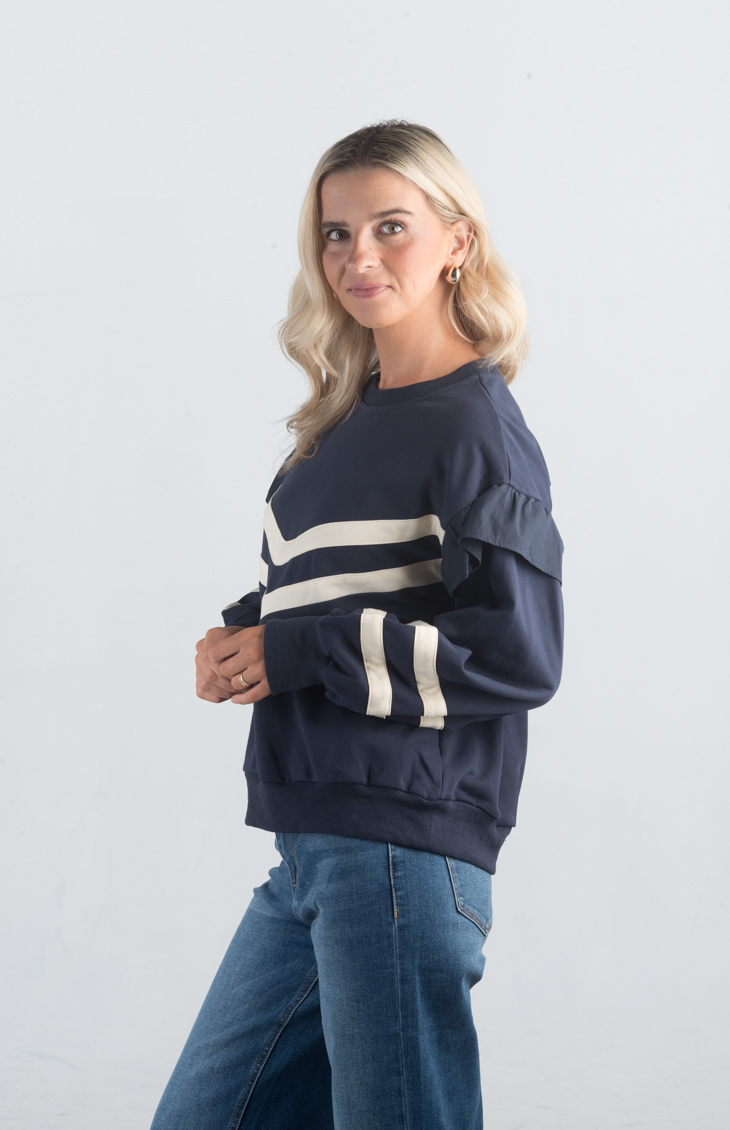 Introducing the Darlene Top, a chic navy sweater featuring white asymmetrical stripes and a delicate ruffle detail on the long sleeves. This unique design adds a touch of elegance and flair to your wardrobe, making it perfect for both casual and sophisticated looks.

Fabric: 85% Cotton, 15% Polyester

Size Guide: Fits True To Size, Model is Wearing a Size S

Available at our boutiques in Chicago, Lake Geneva, and Milwaukee. (Item availability may vary by location.)