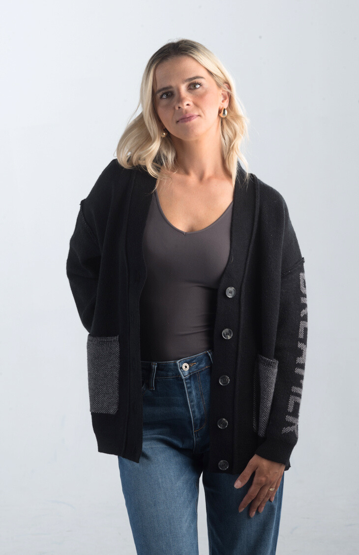 Introducing the Vital Moment Cardigan, a chic black and gray cardigan featuring unique "Dreamer" text on the sleeves. With front pockets and a button-up design, this cardigan combines comfort and style, making it a versatile addition to your wardrobe.

Fabric: 40% Acrylic, 30% Polyester, 30% PBT

Size Guide: Fits True To Size, Model is Wearing a Size S

Available at our boutiques in Chicago, Lake Geneva, and Milwaukee. (Item availability may vary by location.)